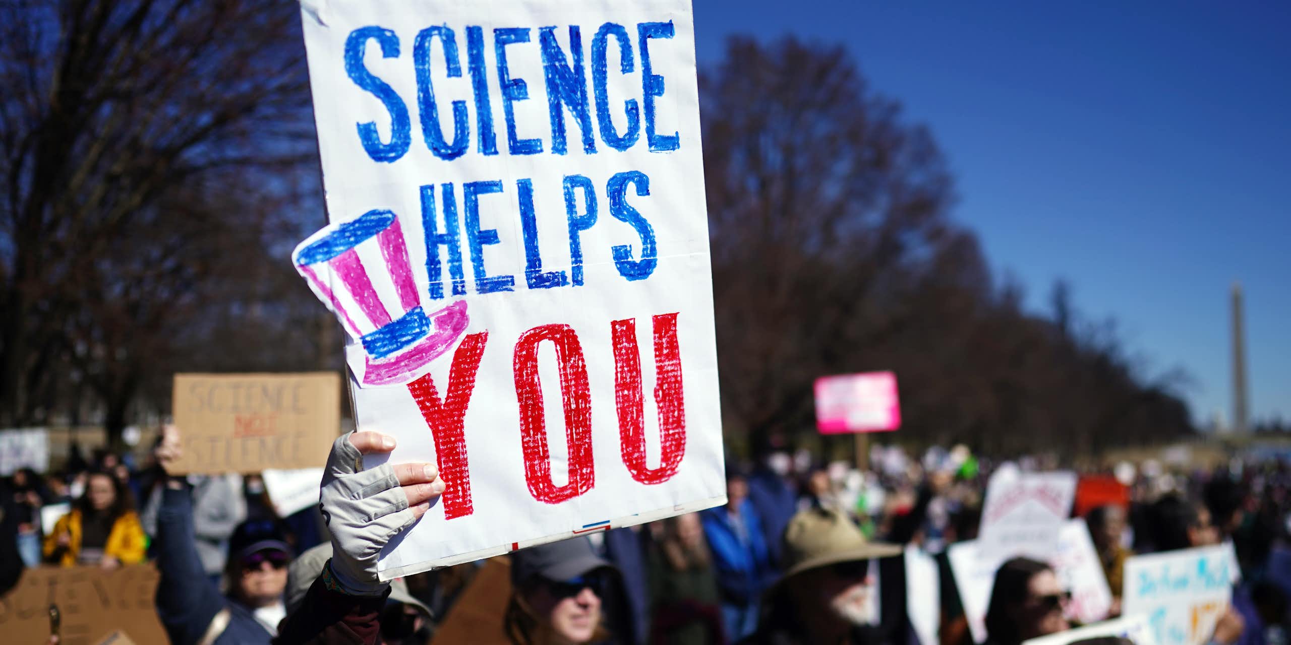 A sign saying science helps you held up by a protestor. 