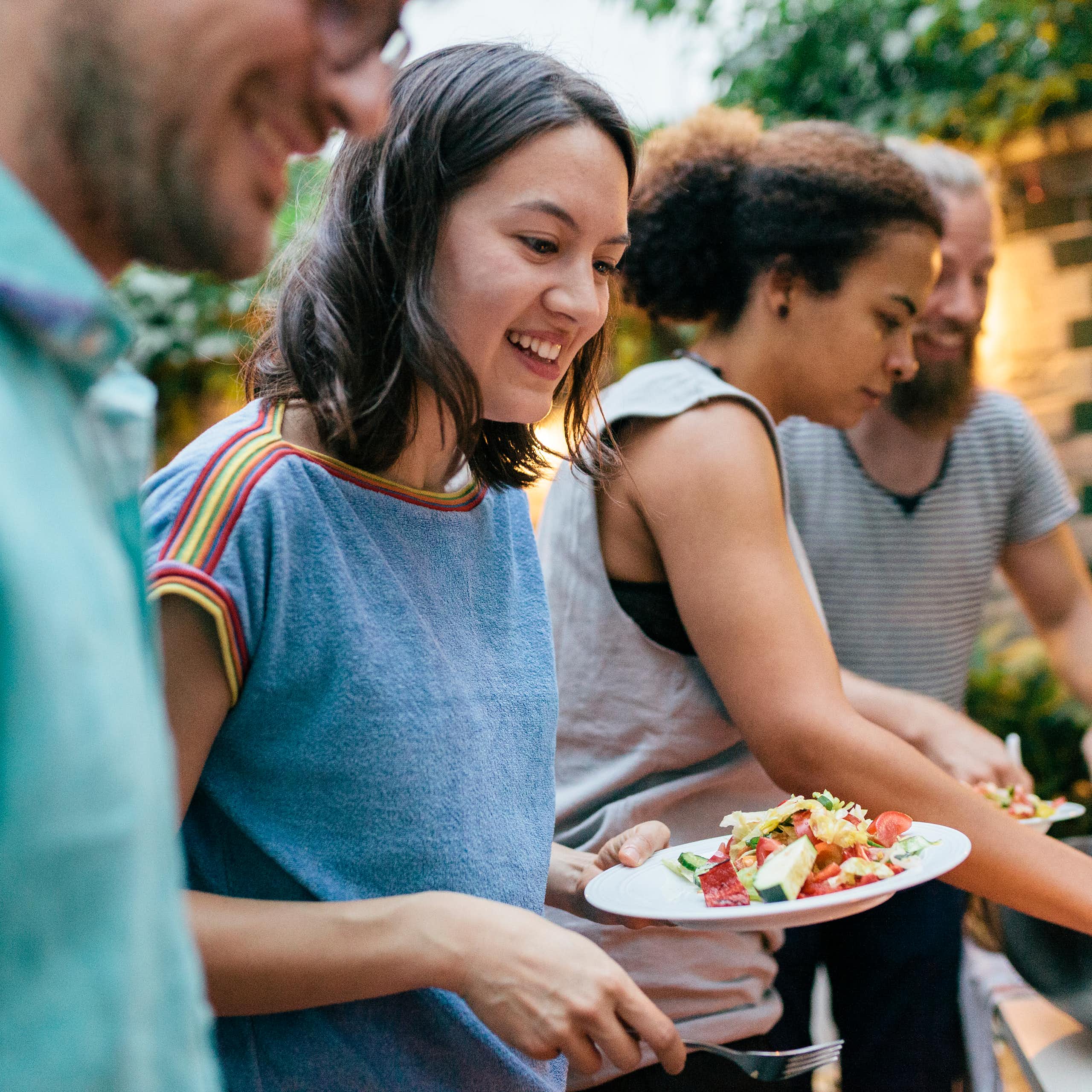 Friends at a barbequeue fill their plates with food.