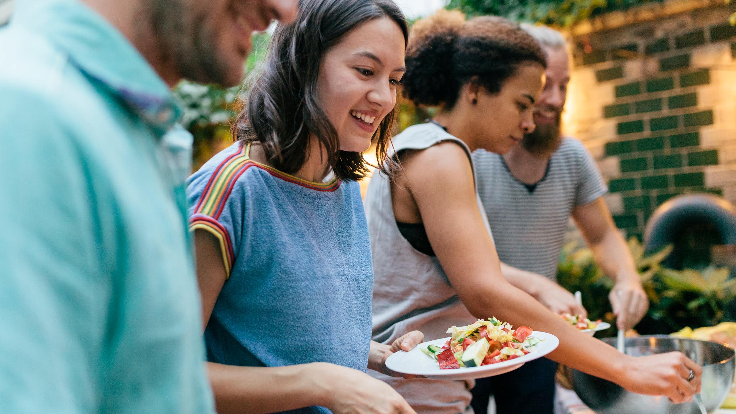 Friends at a barbequeue fill their plates with food.
