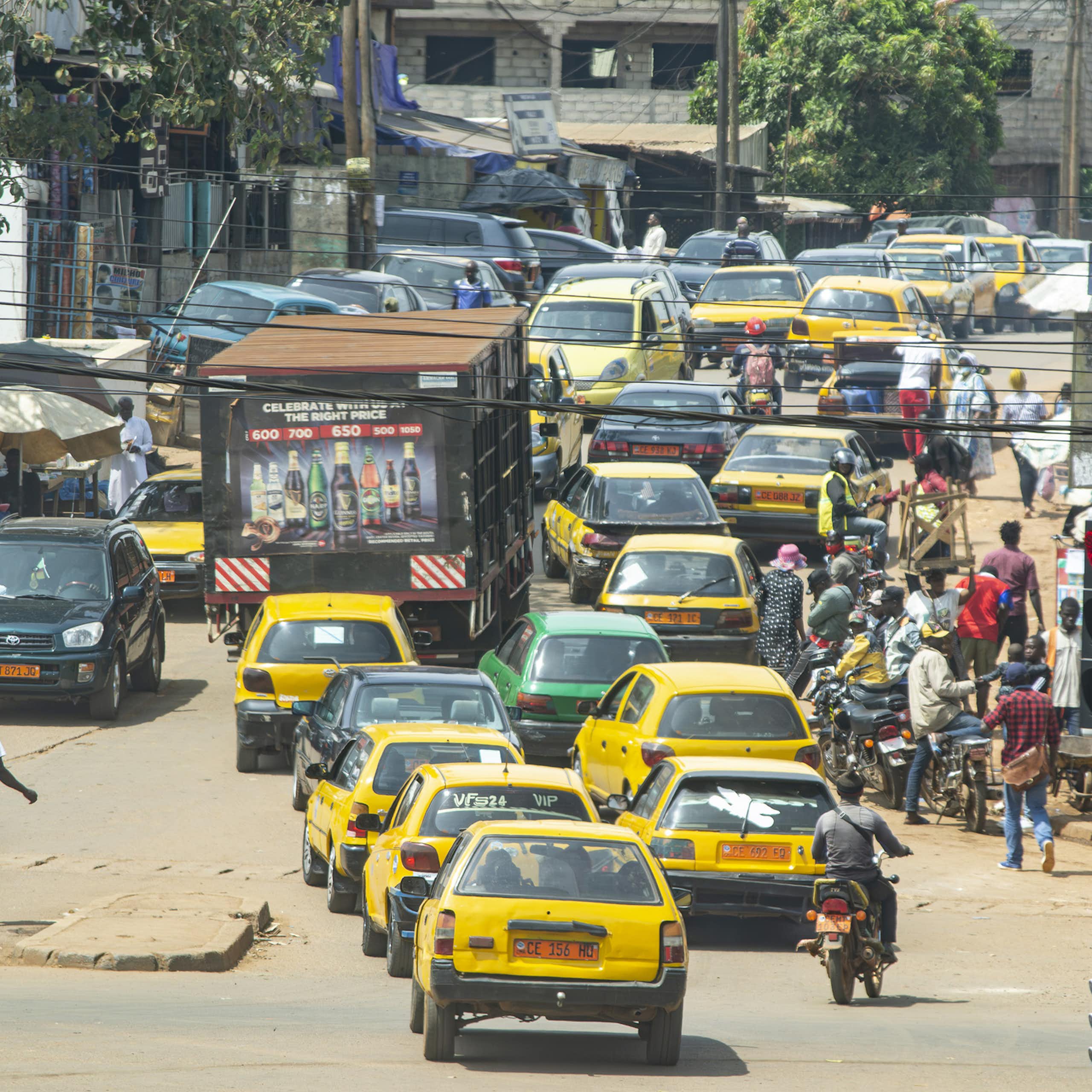 Busy urban road with cars, truck, motorcycles and pedestrians