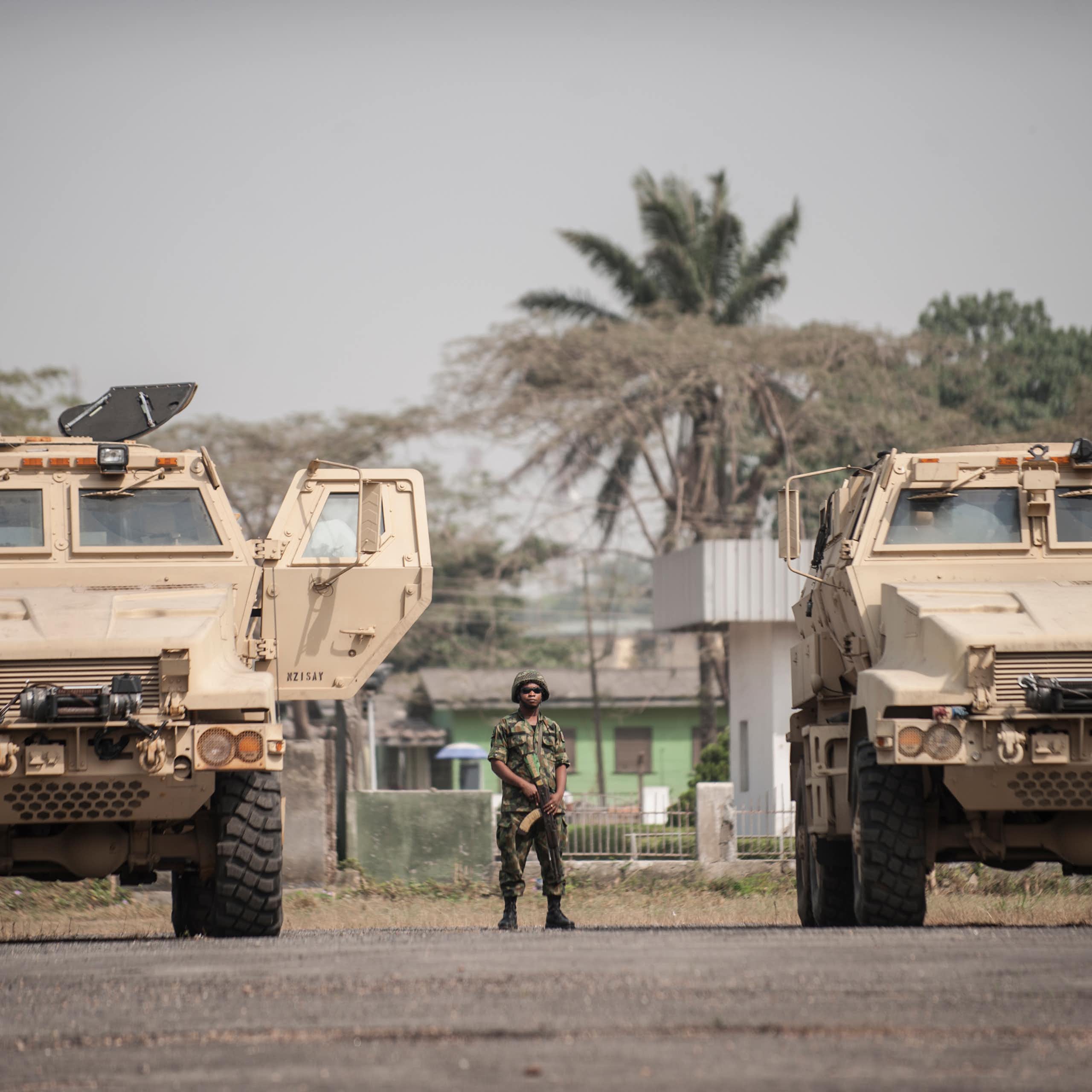 A soldier standing in between armoured vehicles