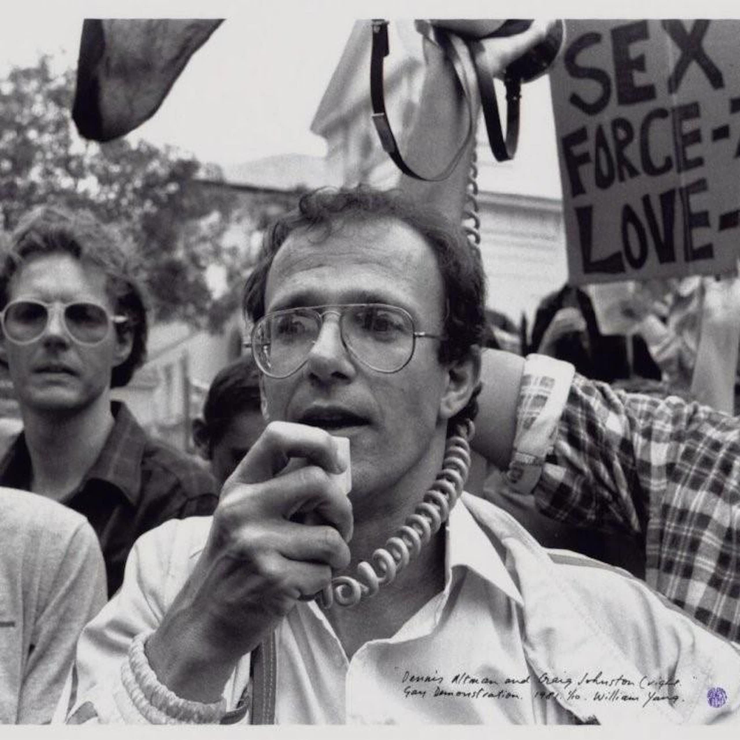 a man with glasses talking into a megaphone at a rally