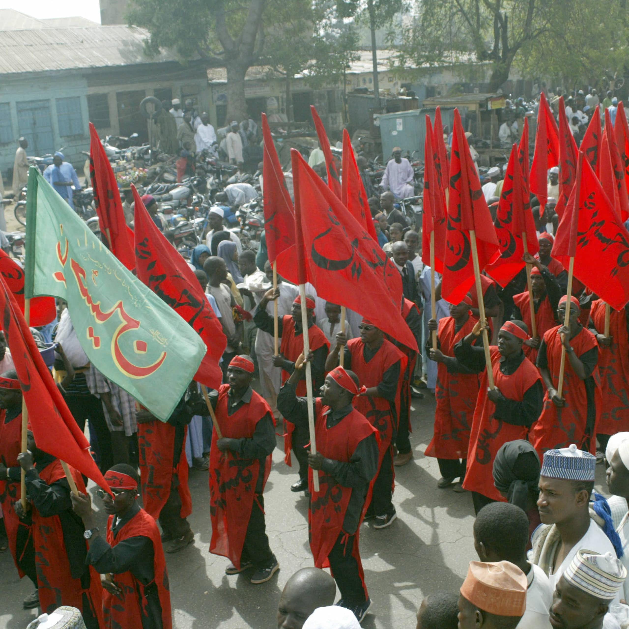 People with red clothing and red flags, gathered in a crowd outdoors