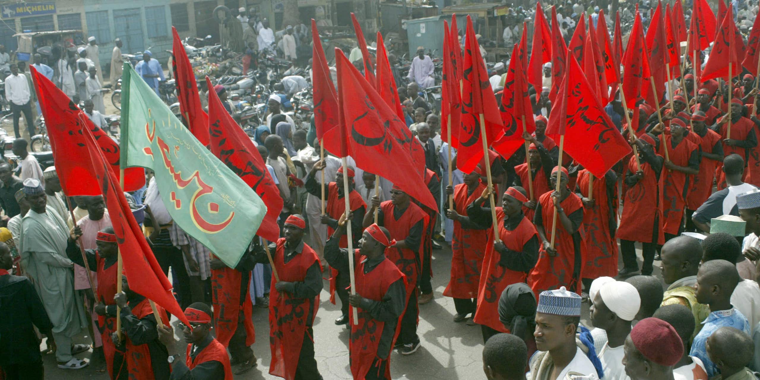 People with red clothing and red flags, gathered in a crowd outdoors