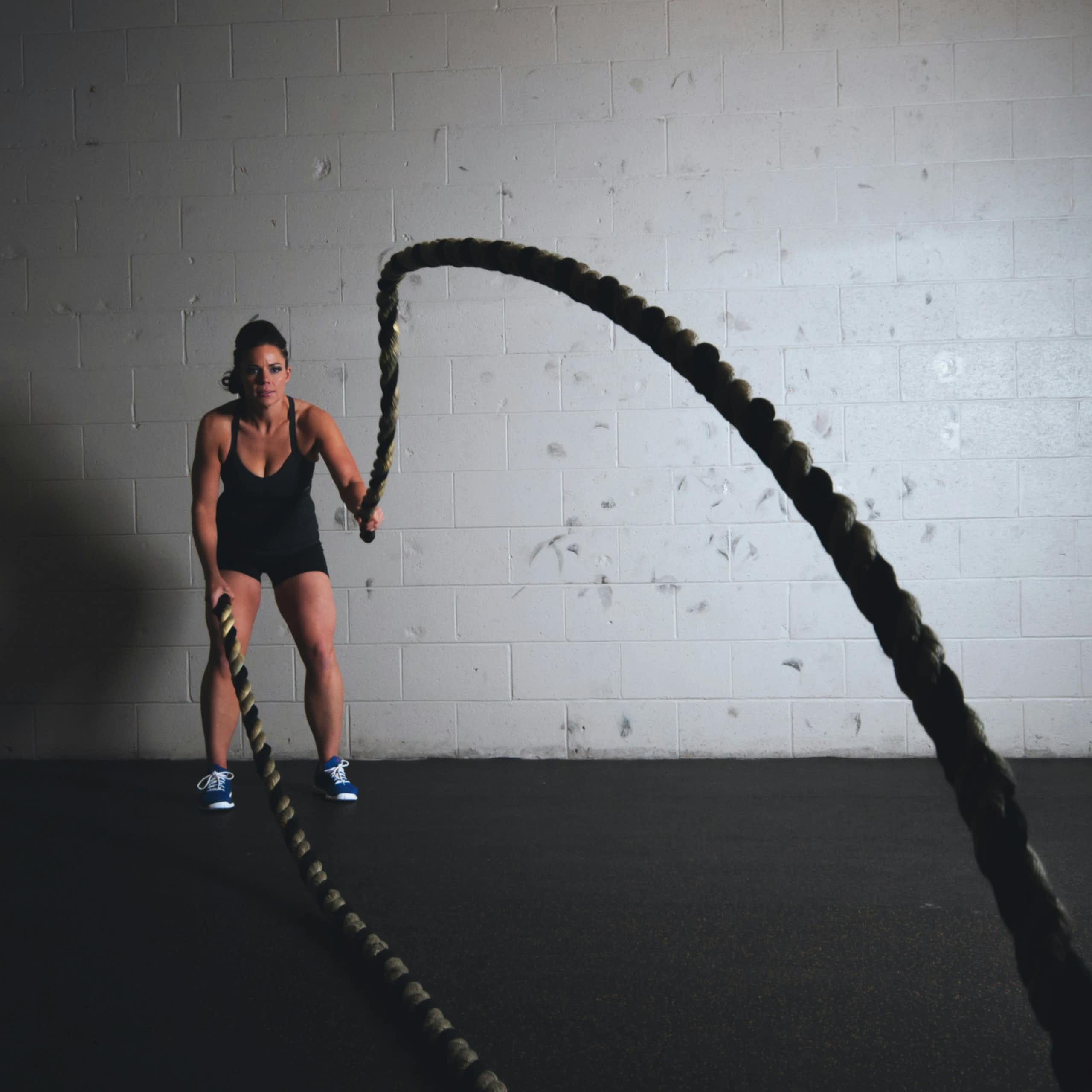 A woman lifting thick ropes in a gym. 