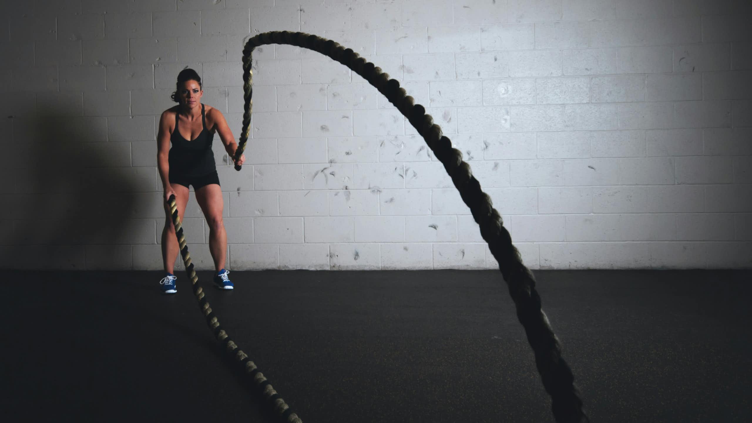 A woman lifting thick ropes in a gym. 