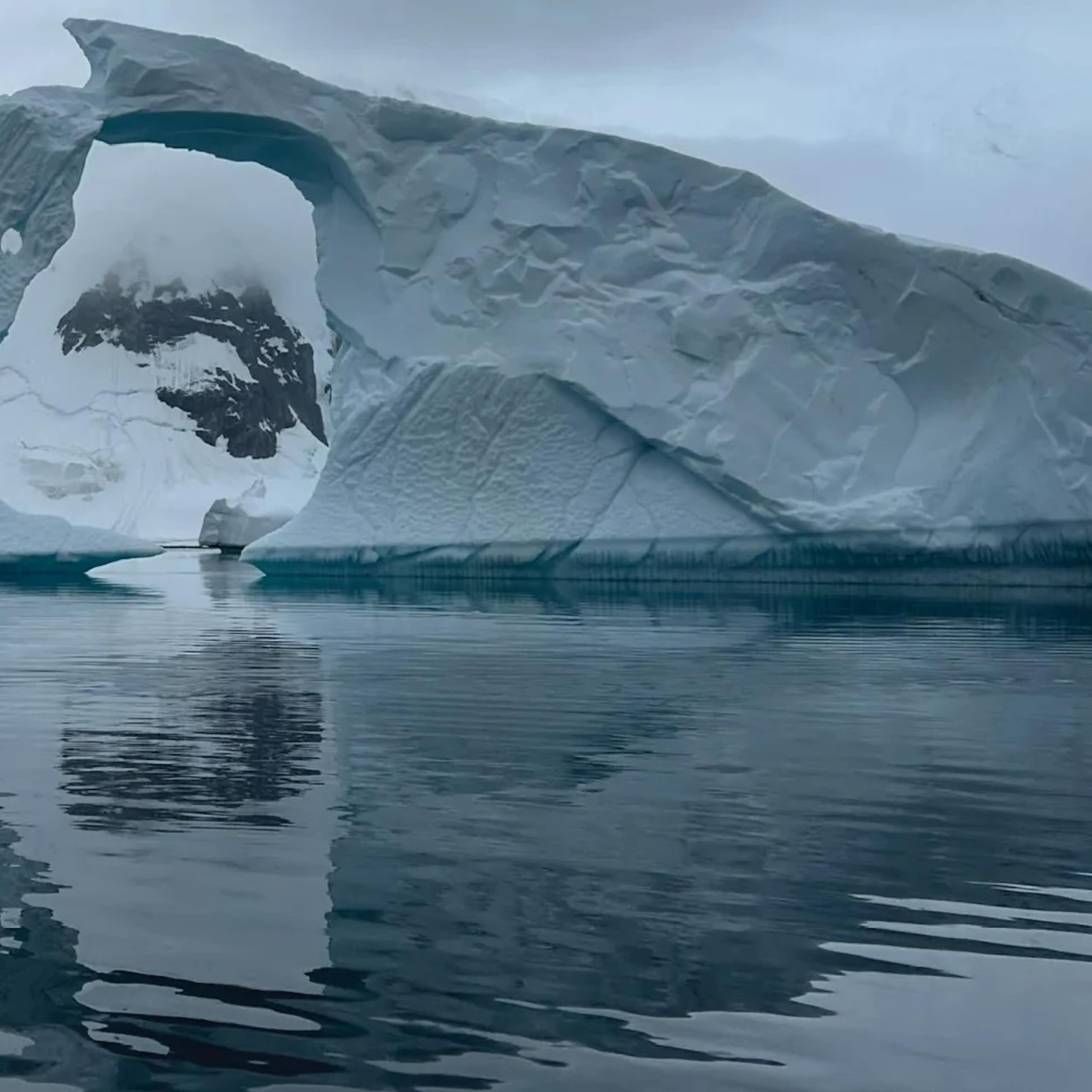 An iceberg with a hole in it looks sculptural and foreboding.