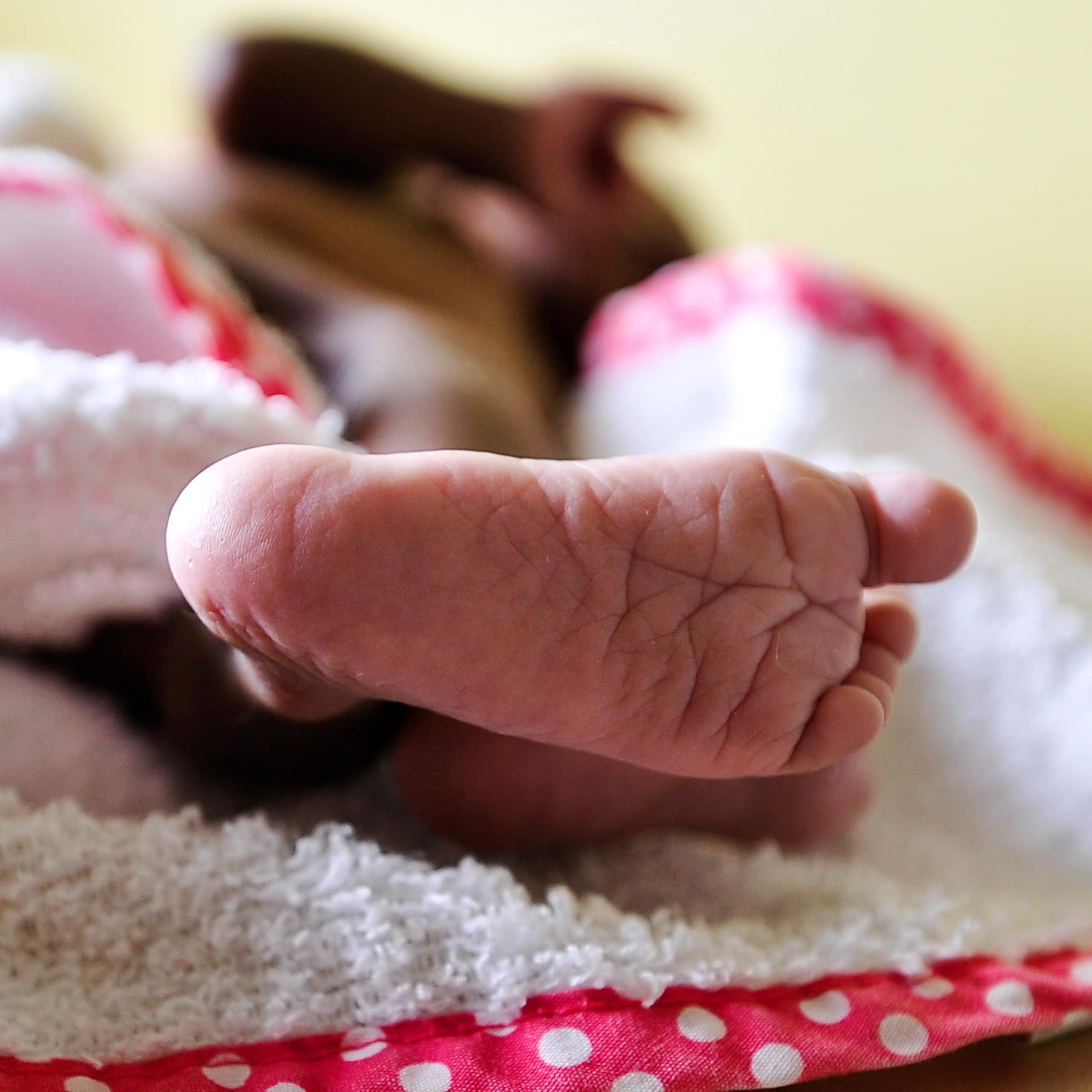 Baby sleeping on a blanket; only the foot is visible