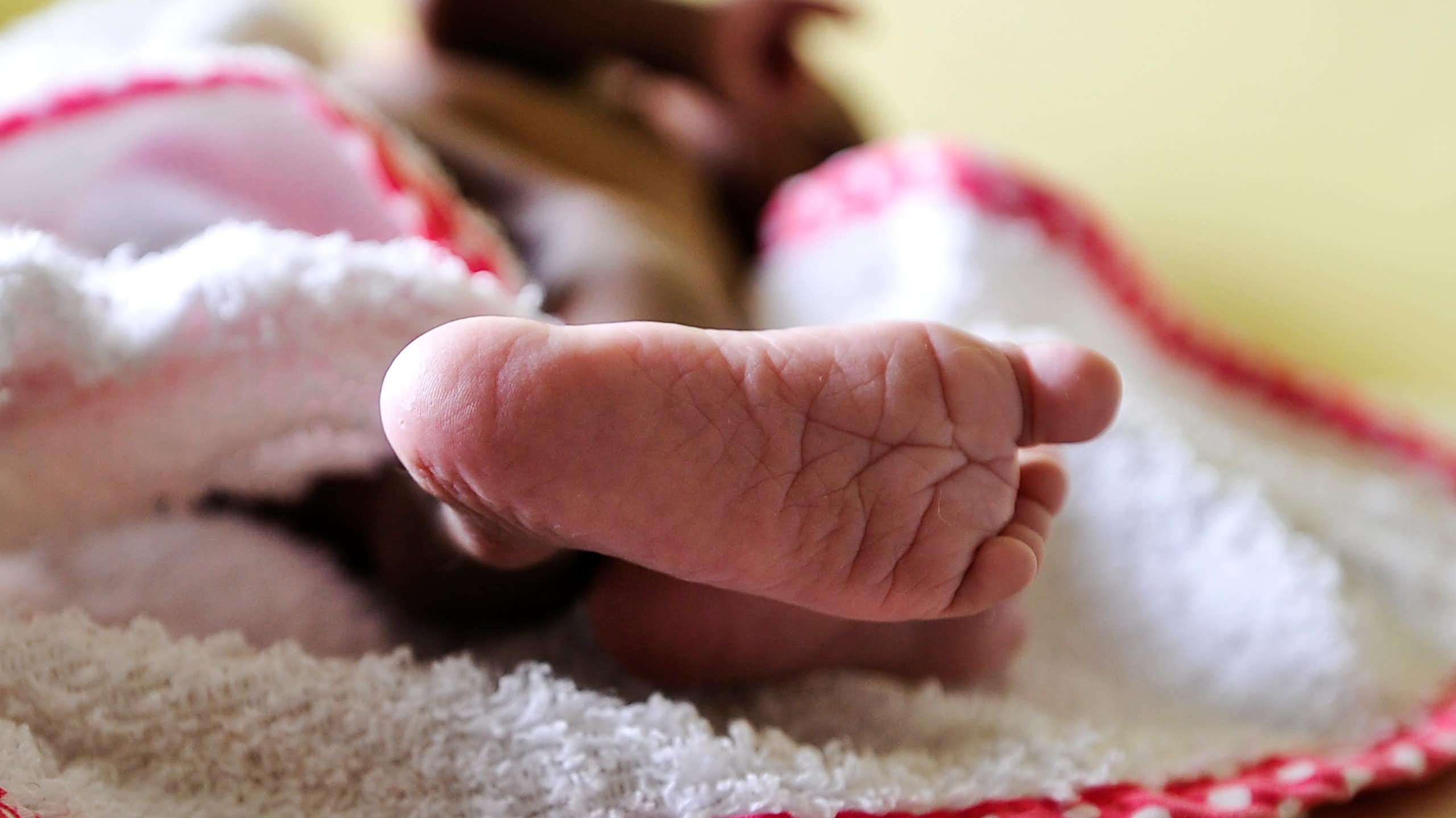 Baby sleeping on a blanket; only the foot is visible