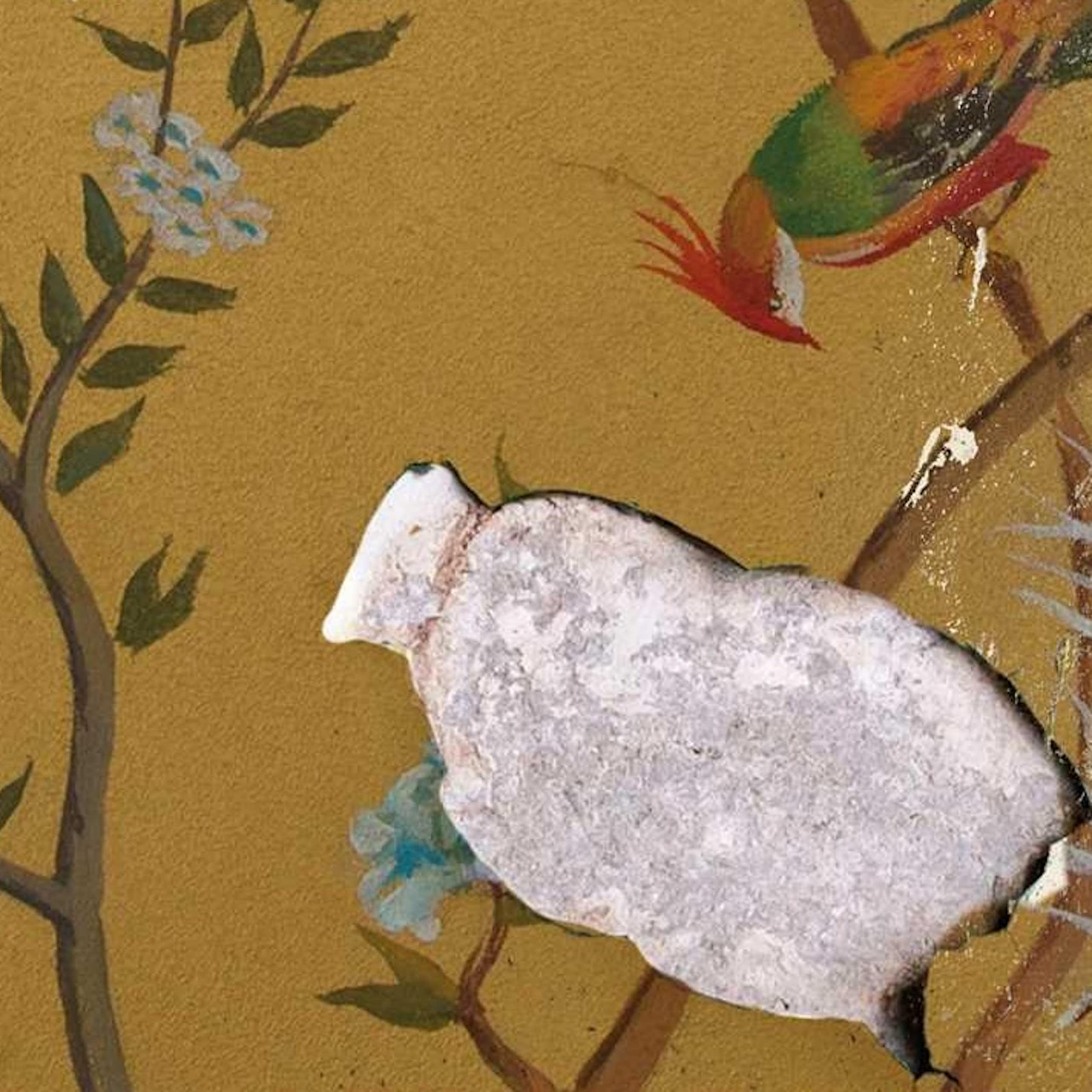 Old wallpaper showing birds in delicate branches of a tree is peeling, revealing cemenrt beneath it.