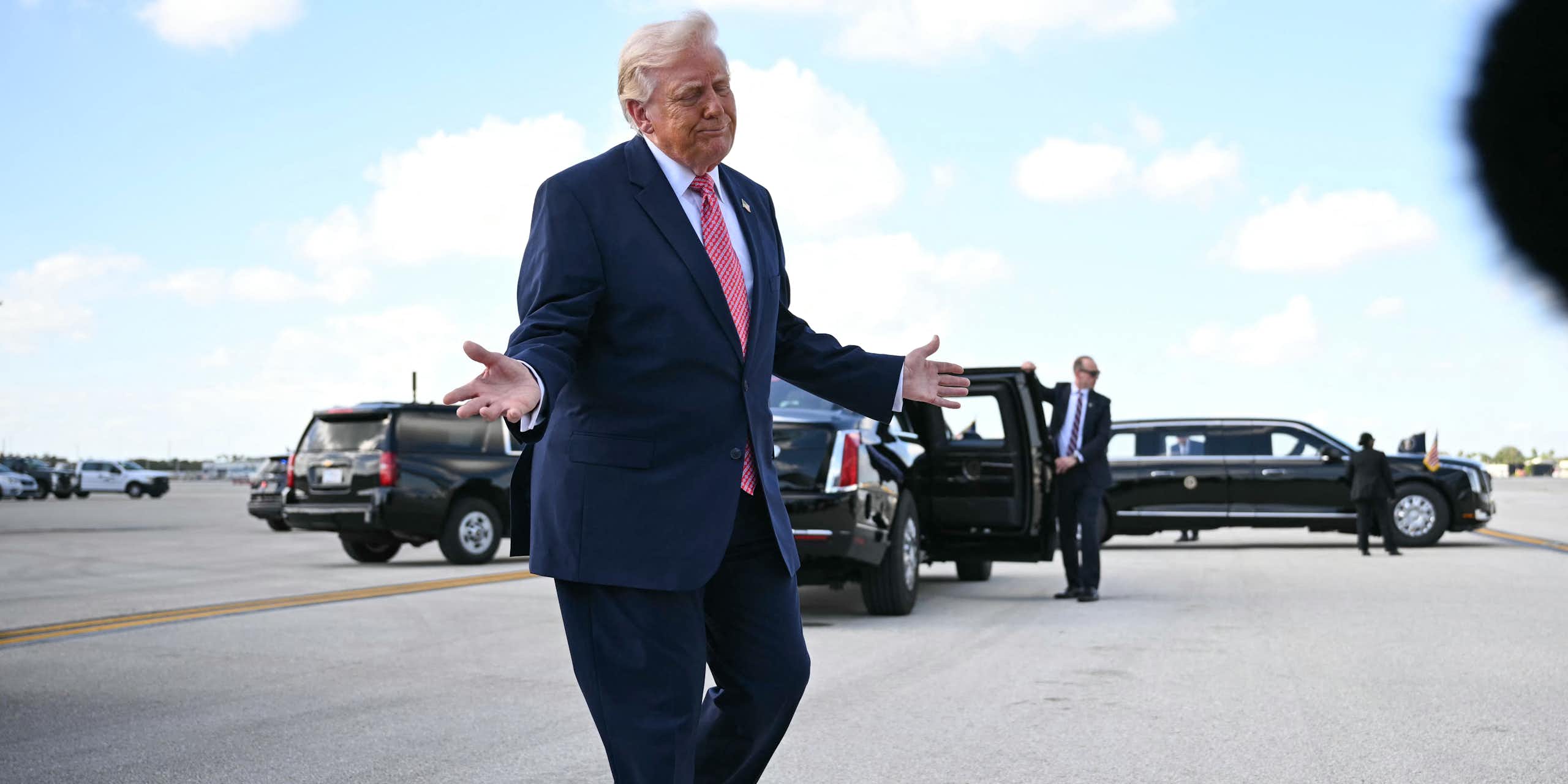 A man in a suit gesticulates with his hands