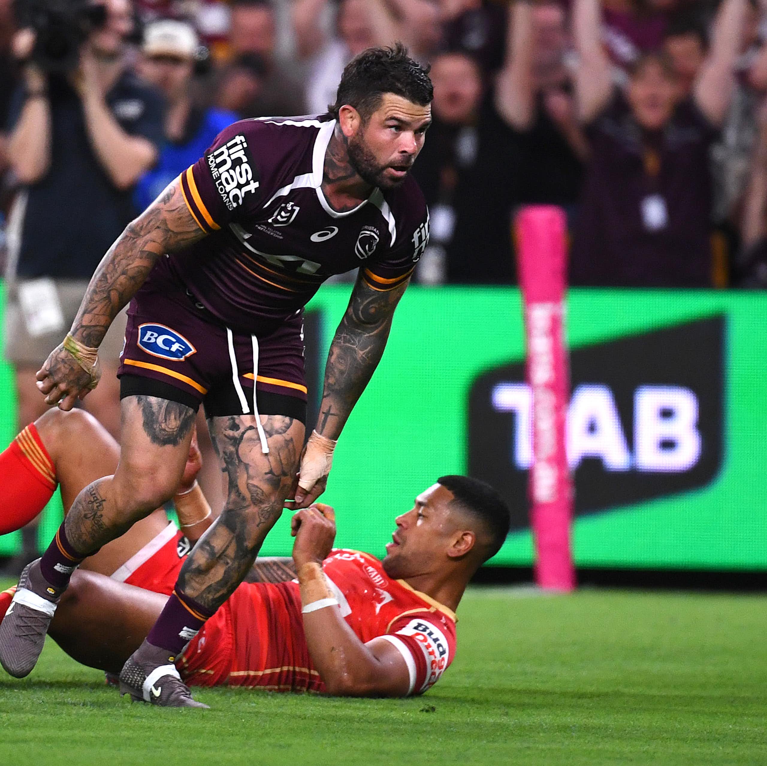Adam Reynolds of the Broncos scores a try against the Dolphins, with TAB signage showing on the sidelines.